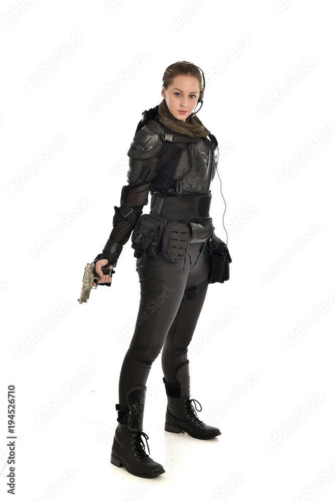 full length portrait of female  soldier wearing black  tactical armour, holding a gun, isolated on white studio background.