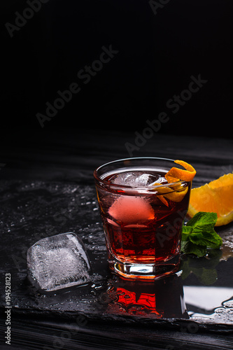 Mezcal Negroni cocktail. Italian aperitivo. Citrus peel. Ice.