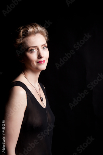 Portrait of a beautiful woman in a black decollete dress on a black background in the studio