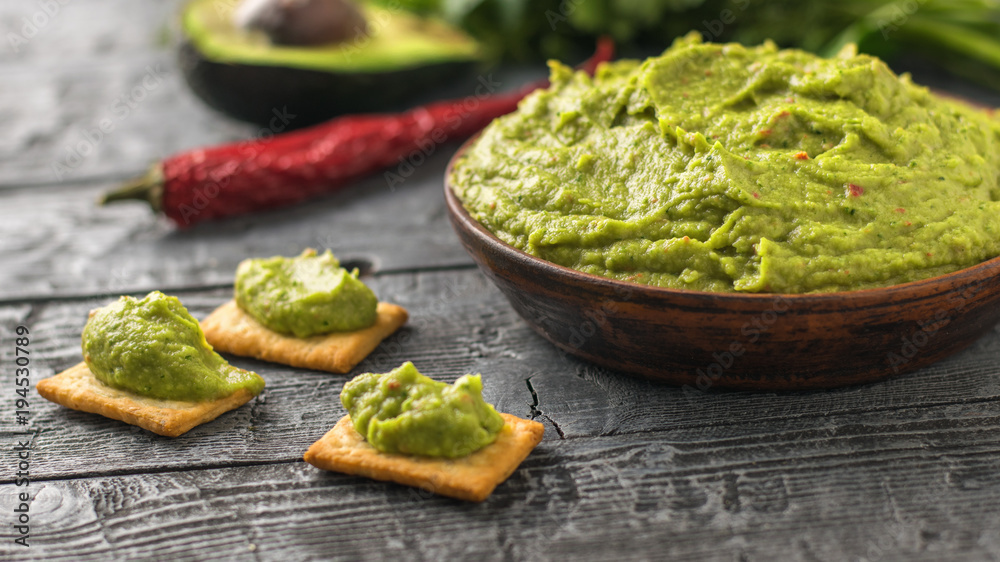 Clay bowl with fresh guacamole, tomatoes, lemon, chips, avocado and garlic on wooden table. Diet vegetarian Mexican food avocado. Clay bowl with fresh guacamole, tomatoes, lemon, chips, avocado and garlic on wooden table. Diet vegetarian Mexican food avocado.