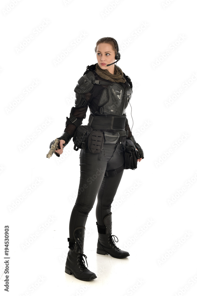 full length portrait of female soldier wearing black tactical armour,  holding a gun, isolated on white studio background. Stock Photo