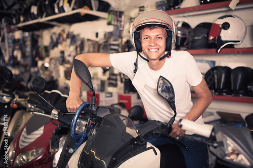Portrait of glad male in helmet on motorbike in the store