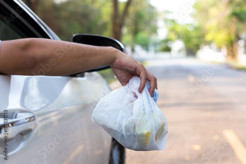 man's hand throwing trash out of car window, close up