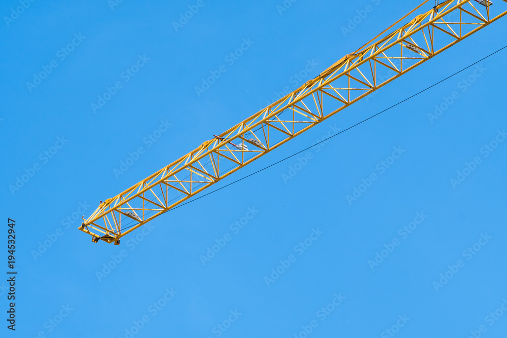 Yellow construction crane on top of the building under construction site in day time with blue sky background Yellow construction crane on top of the building under construction site in day time with blue sky background