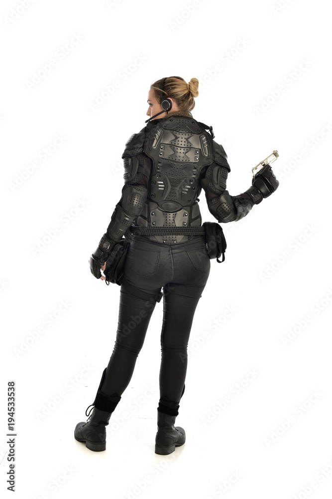 full length portrait of female  soldier wearing black  tactical armour, holding a gun, isolated on white studio background.