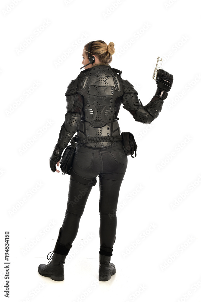 full length portrait of female  soldier wearing black  tactical armour, holding a gun, isolated on white studio background.