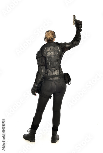 full length portrait of female soldier wearing black tactical armour, holding a gun, isolated on white studio background.