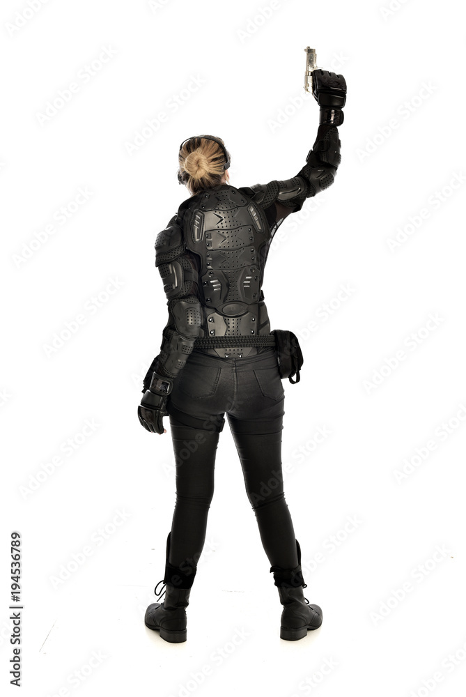 full length portrait of female  soldier wearing black  tactical armour, holding a gun, isolated on white studio background.