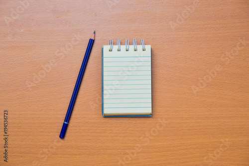 Notepad with pencil on wood board background.using wallpaper for education, business photo.Take note of the product for book with paper and concept, object or copy space.
