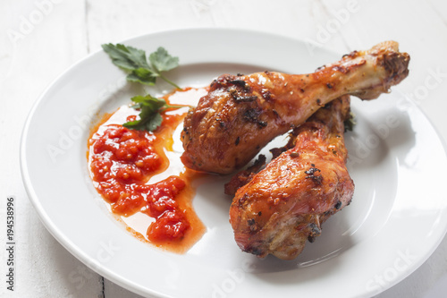 two appetizing baked sharp chicken legs with sauce on a plate