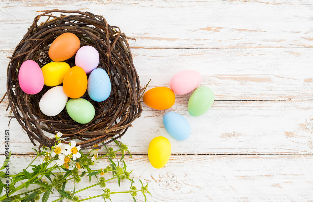 Colorful Easter eggs in nest with flower on rustic wooden planks background in white paint . Holiday in spring season. vintage color tone style. top view composition. Colorful Easter eggs in nest with flower on rustic wooden planks background in white paint . Holiday in spring season. vintage color tone style. top view composition.