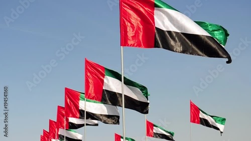 United Arab Emirates flags over blue sky.