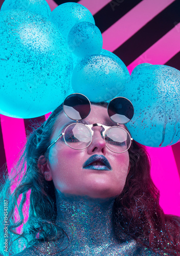 Young attractive girl in makeup, in glasses and balloons on the head