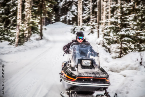 A man is riding a snowmobile in the winter forest