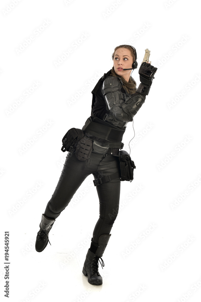 full length portrait of female  soldier wearing black  tactical armour, holding a gun, isolated on white studio background.
