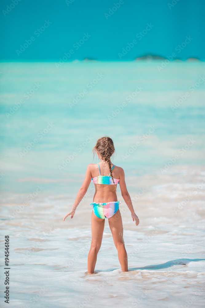 Happy little girl running and splashing at shallow water at beach having a lot of fun on vacation Happy little girl running and splashing at shallow water at beach having a lot of fun on vacation