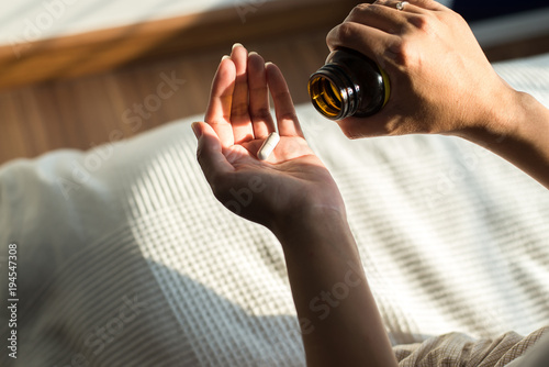 Woman hands with pills on spilling pills out of bottle,Female hand holding a medicine photo