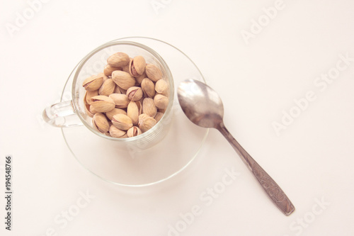 Glass cup and pistachio nuts on white background. Various nuts. Top view with copy space.