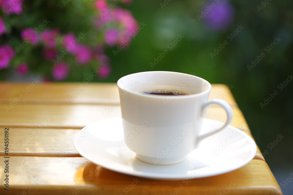 Coffee in a white cup on wooden table at outdoor