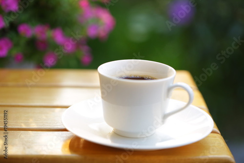 Coffee in a white cup on wooden table at outdoor
