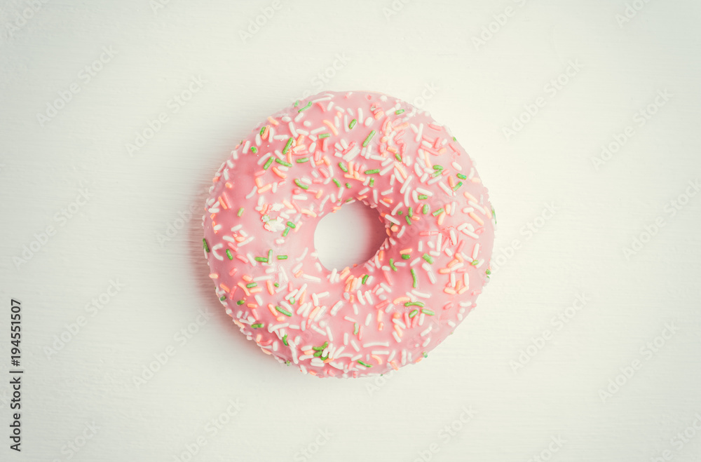 Donut with sprinkles on the rustic wooden background. Selective focus. Donut with sprinkles on the rustic wooden background. Selective focus.