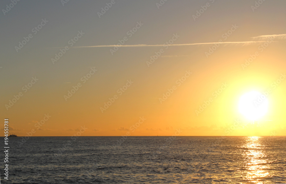 Sunset in sea. Ship on horizon.