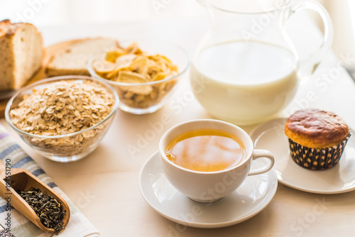 Useful rustic breakfast on the table - tea, oatmeal, milk and fresh cake - healthy eating concept