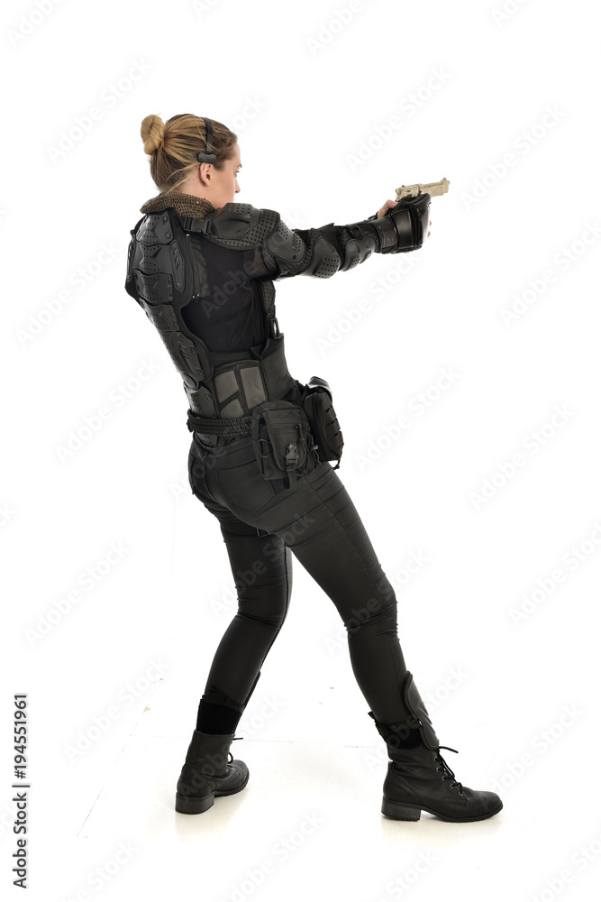 full length portrait of female soldier wearing black tactical armour, holding a gun, isolated on white studio background. full length portrait of female soldier wearing black tactical armour, holding a gun, isolated on white studio background.