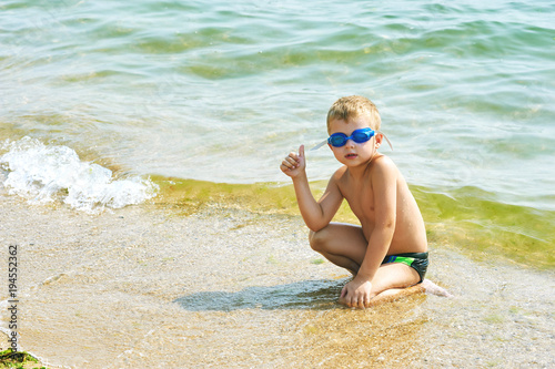 boy with glasses for swimming resting lying on the shore