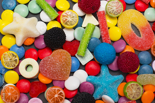 Multicolored candy and lollipops on a gray background.