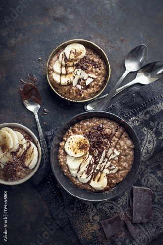 morning chocolate oat porridge with fresh bananas on black background