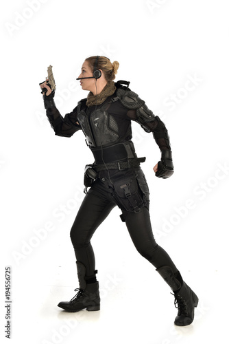 full length portrait of female  soldier wearing black  tactical armour, holding a gun, isolated on white studio background. © faestock