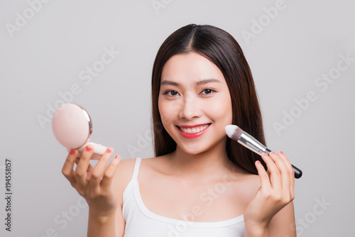 Young asian beautiful woman holding foundation box and brush