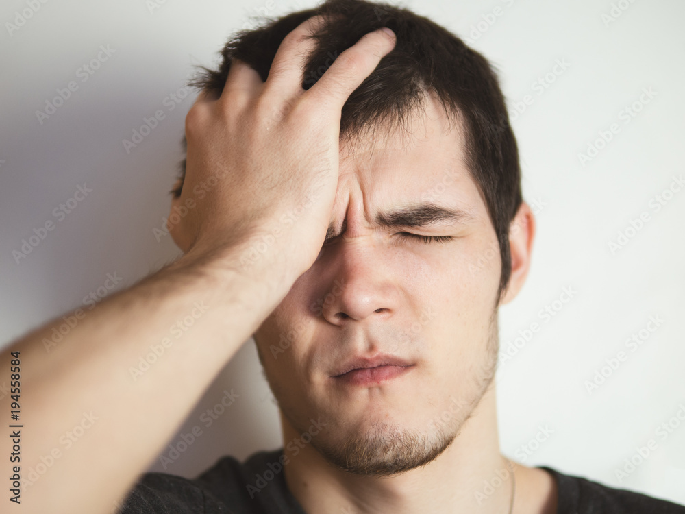 Fototapeta premium young man holding onto his head. Headache
