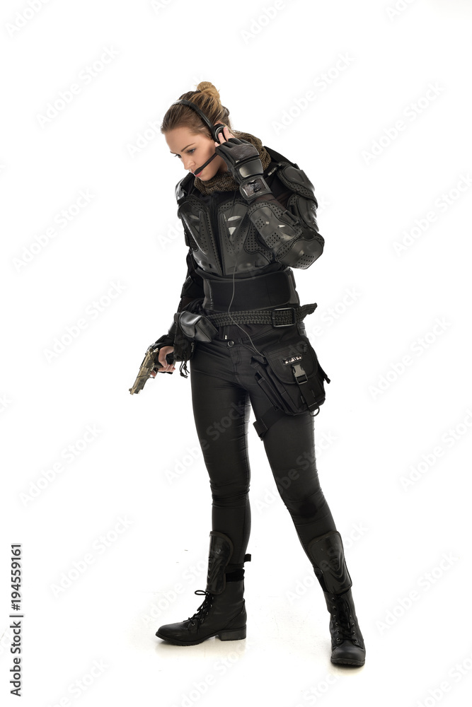 full length portrait of female  soldier wearing black  tactical armour, holding a gun, isolated on white studio background.