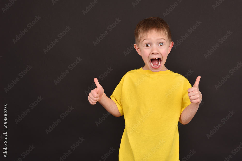 A boy on a dark background. Shooting a child in the studio. A young man in a yellow T-shirt. A boy on a dark background. Shooting a child in the studio. A young man in a yellow T-shirt.