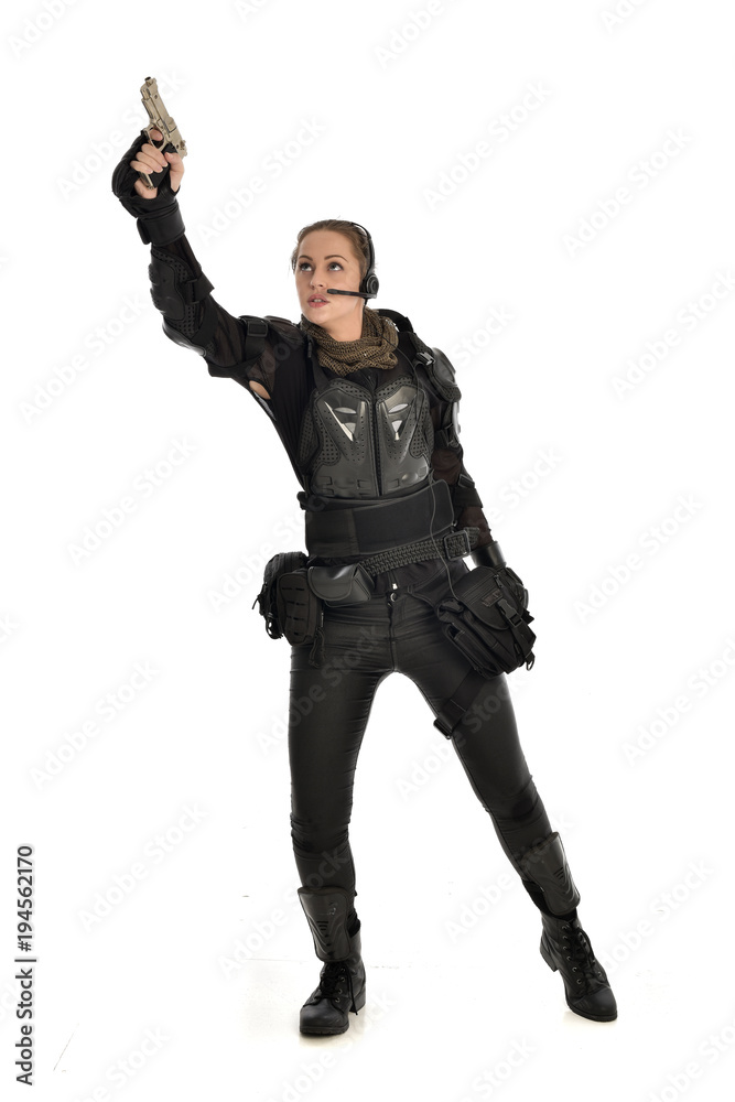 full length portrait of female soldier wearing black tactical armour, holding a gun, isolated on white studio background. full length portrait of female soldier wearing black tactical armour, holding a gun, isolated on white studio background.