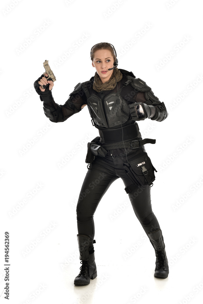full length portrait of female soldier wearing black tactical armour, holding a gun, isolated on white studio background. full length portrait of female soldier wearing black tactical armour, holding a gun, isolated on white studio background.