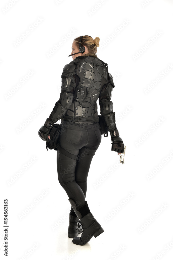 full length portrait of female soldier wearing black tactical armour, holding a gun, isolated on white studio background. full length portrait of female soldier wearing black tactical armour, holding a gun, isolated on white studio background.