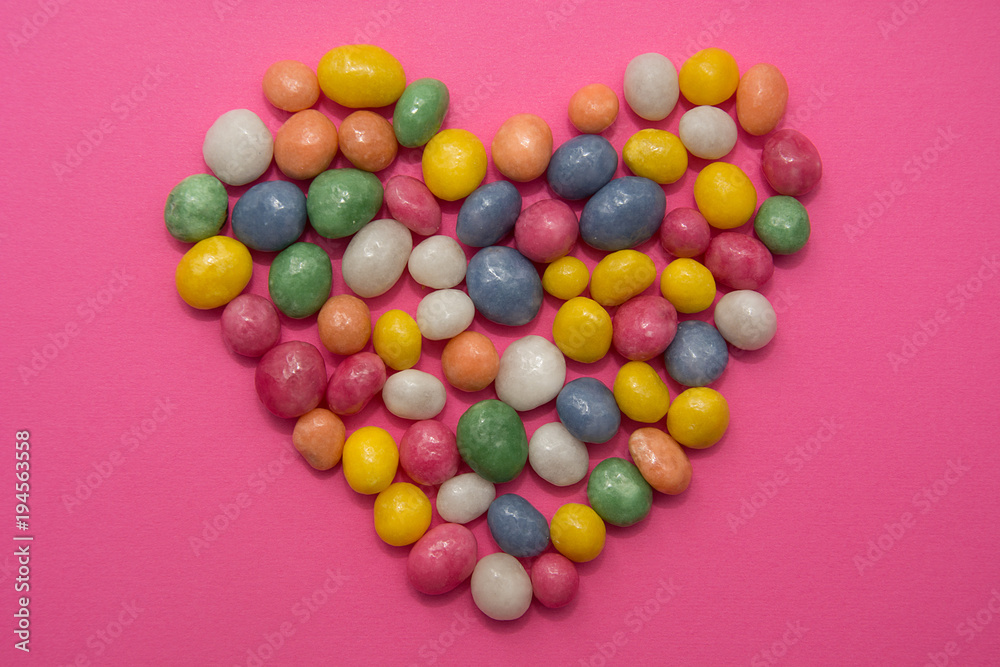 Heart from candies scattered on pink background Heart from candies scattered on pink background