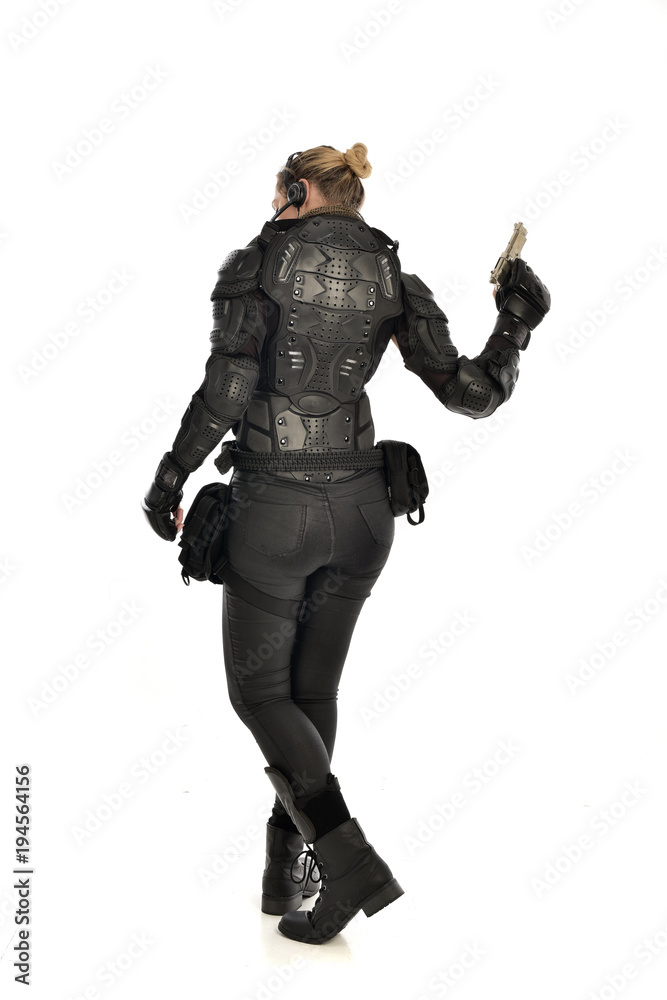 full length portrait of female  soldier wearing black  tactical armour, holding a gun, isolated on white studio background.