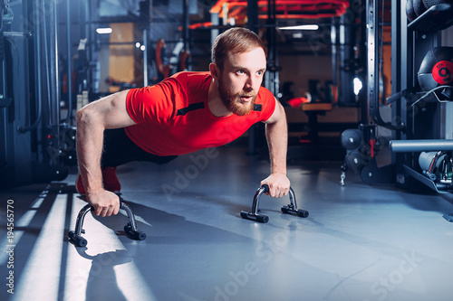 An athlete who does push-up and looking at the camera. Isolated on white background.