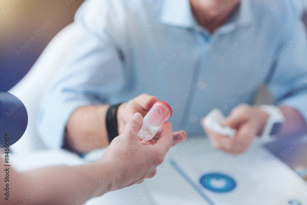 Strong painkiller. Selective focus of a bottle with pills being given to an unhappy moody adult man while sitting at the table