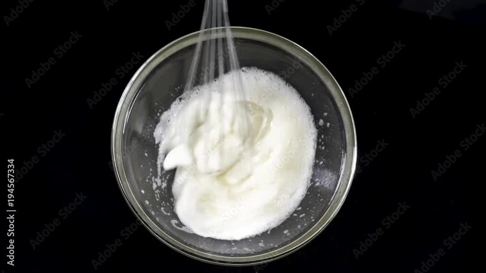 The cook brews the eggs. Whisk egg white. Black background. Slow motions The cook brews the eggs. Whisk egg white. Black background. Slow motions