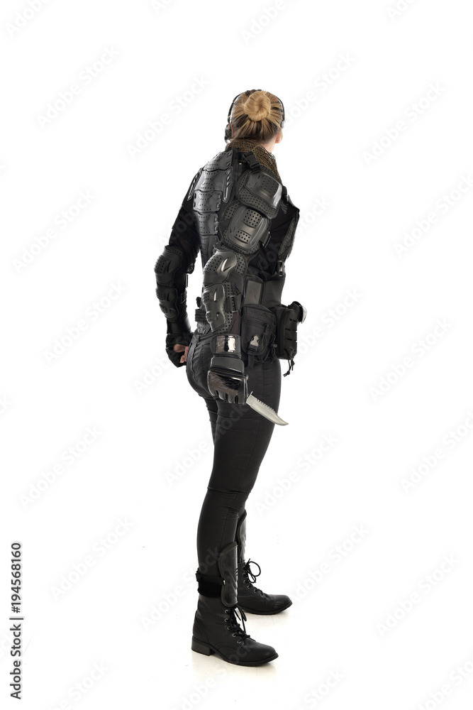 full length portrait of female  soldier wearing black  tactical armour, holding a remote knife, isolated on white studio background.