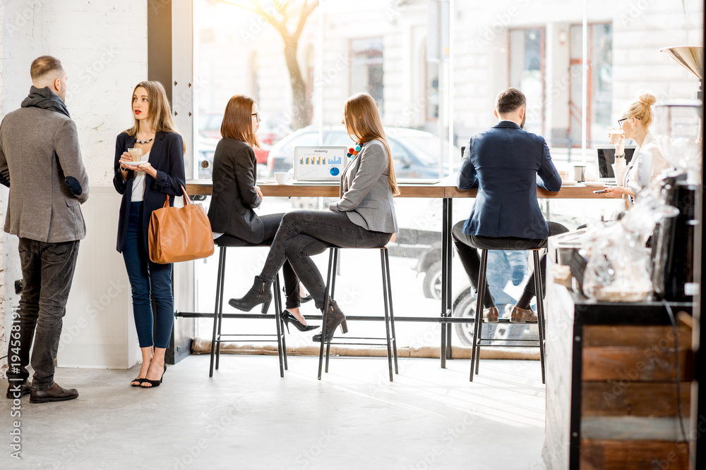 Business people having a conversation during the coffee break near the window in the cafe