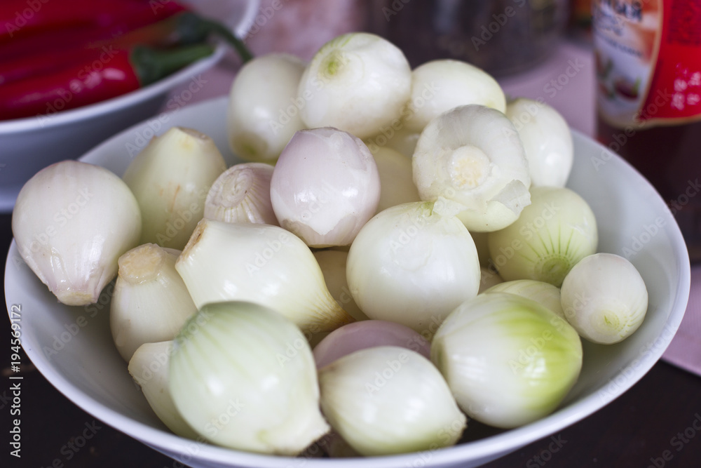 Peeled shallots on a white porcelain dish Peeled shallots on a white porcelain dish