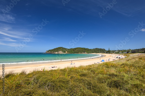 Beautiful wide angle view of Matapouri Beach near Whangarei on the North Island of New Zealand. Grass in the foreground. The close by Mermaid rock pools make it a popular tourist destination. photo