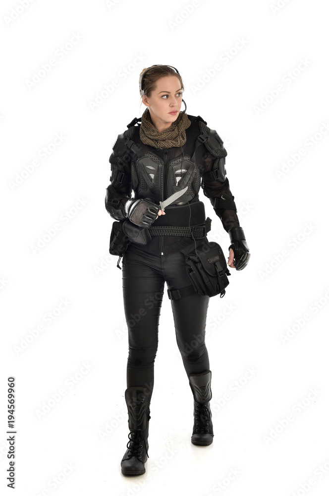 full length portrait of female soldier wearing black tactical armour, holding a remote knife, isolated on white studio background. full length portrait of female soldier wearing black tactical armour, holding a remote knife, isolated on white studio background.