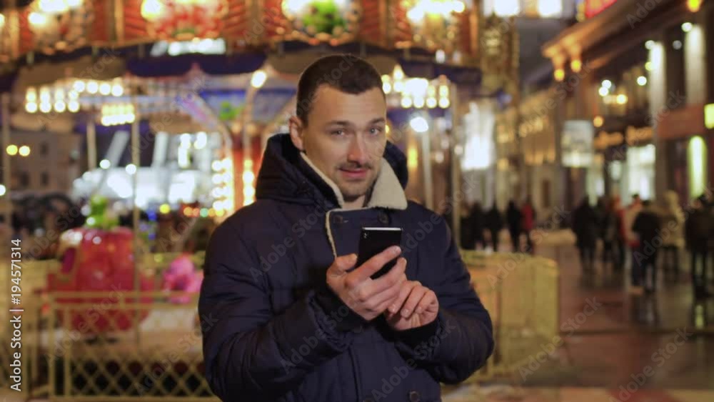 Young guy uses phone in the amusement park Young guy uses phone in the amusement park